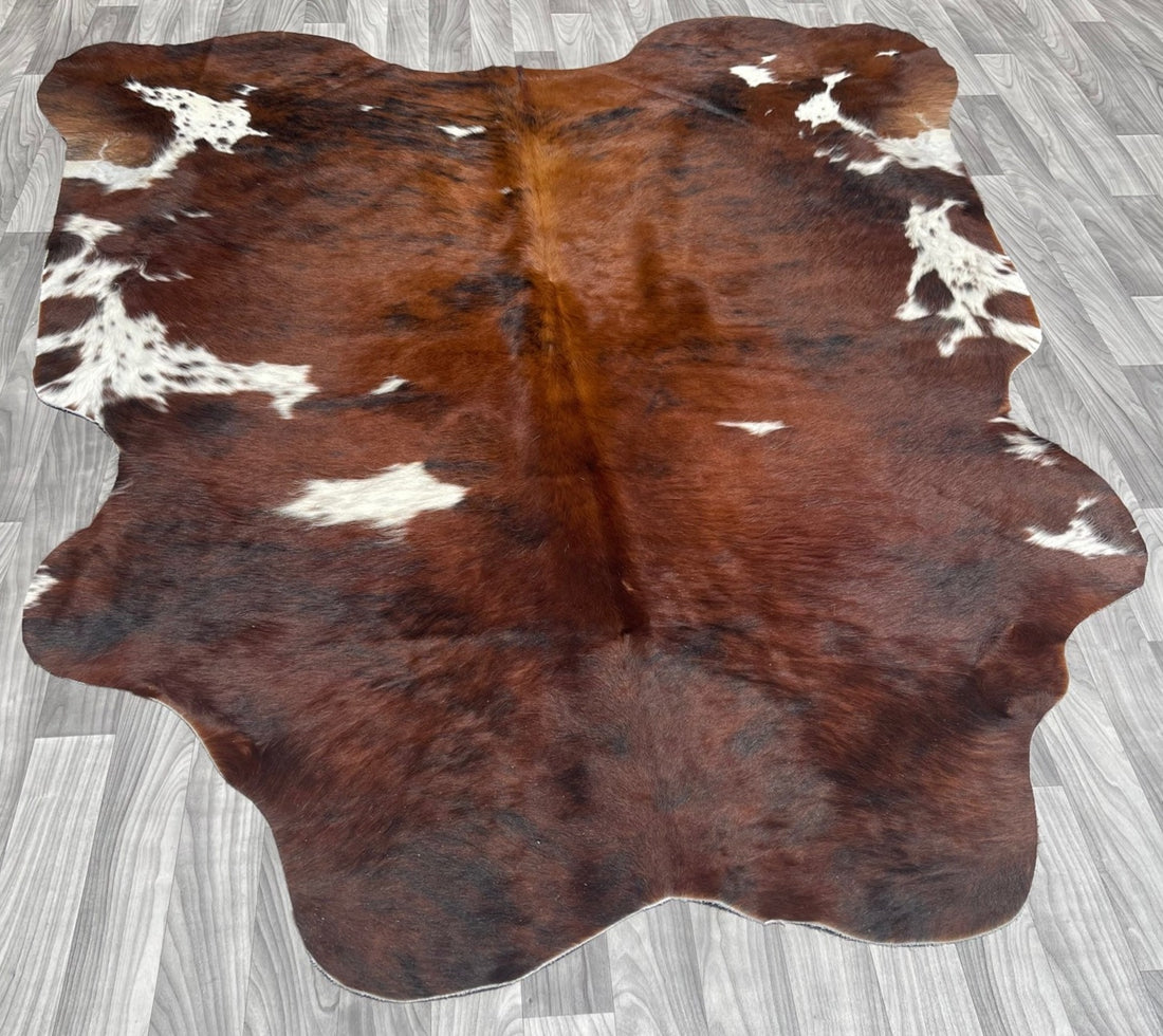 A brown cowhide rug on a grey wooden floor