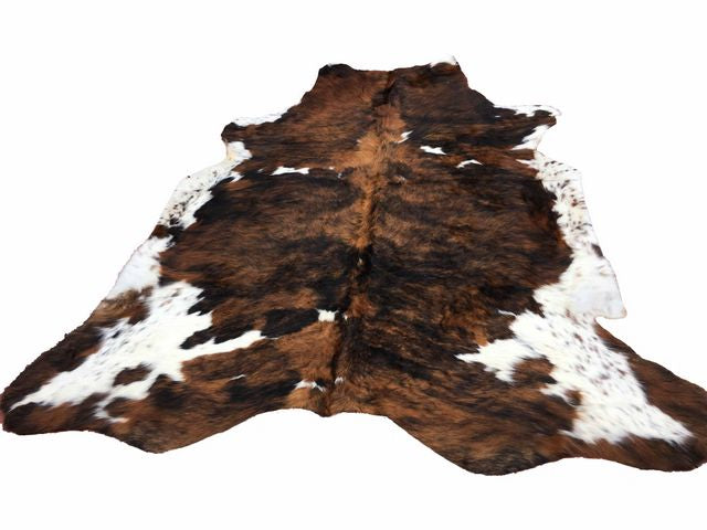 A multi-colored cowhide rug on a grey wooden floor